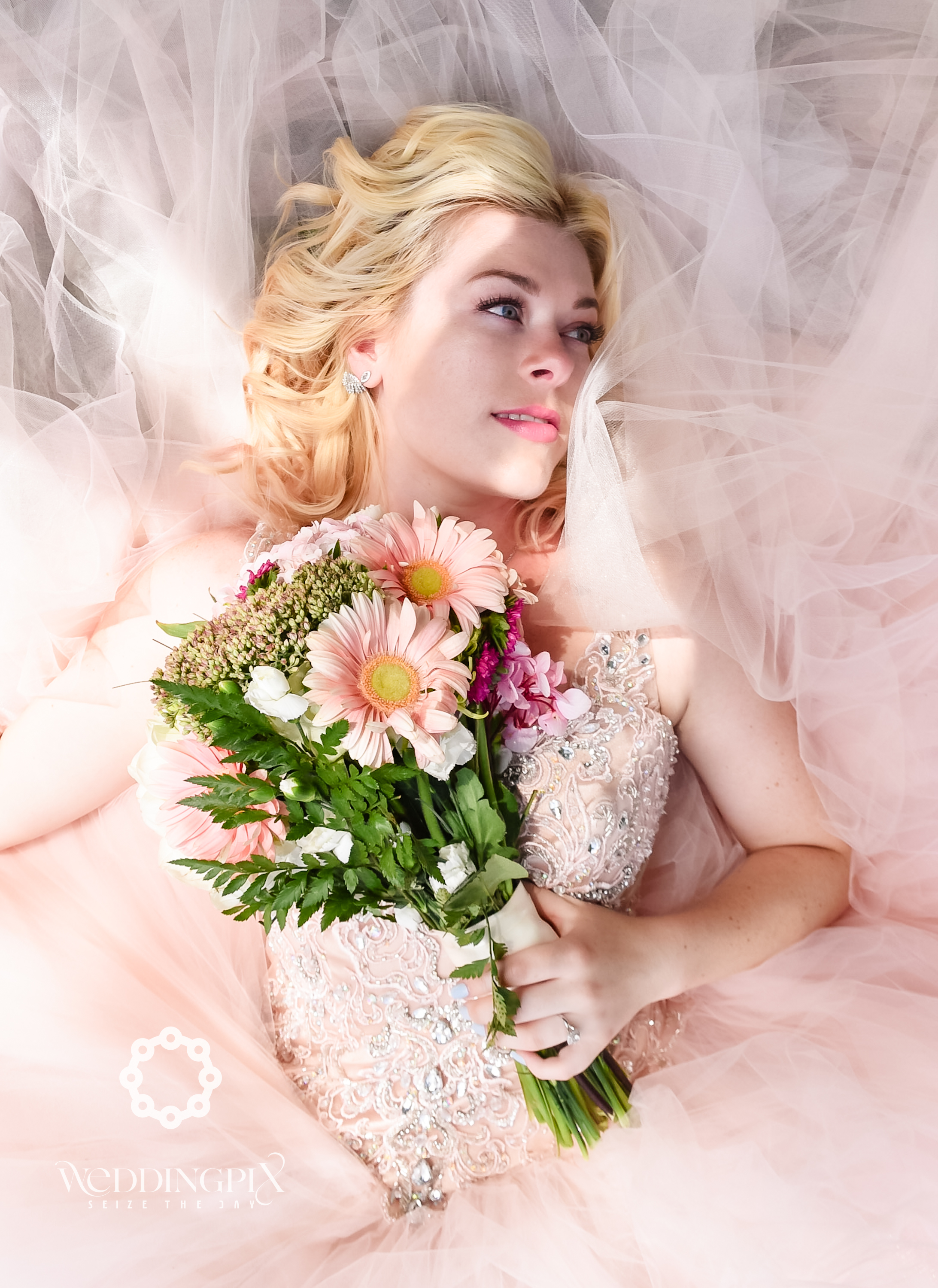 Kitchener-Waterloo bride poses for creative photographer with beautiful pink wedding bouquet and wedding dress